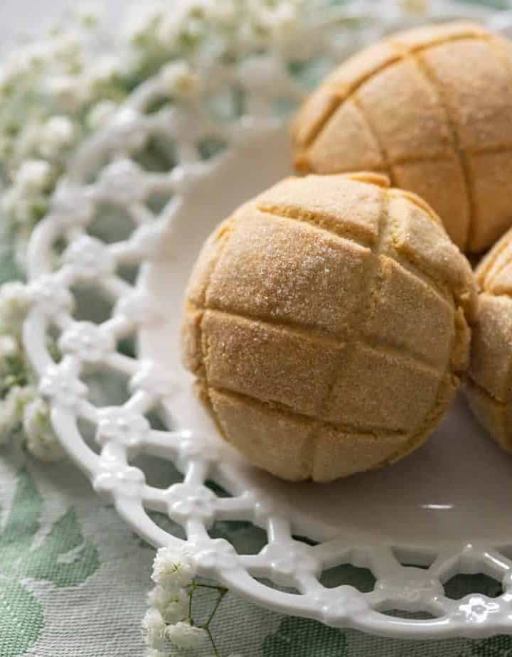 Melon bread on a white plate with flowers and a green cloth napkin.
